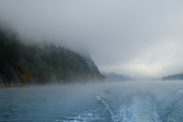 Walk on the Norwegian lake on a boat in the autumn in the fog. Wake of the boat