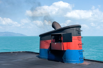Smoke from ferry boat flue during sea with sunlight, sea water and clear sky in background, Thailand