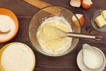 Making dough for baking from fresh ingredients on a rustic wooden table.