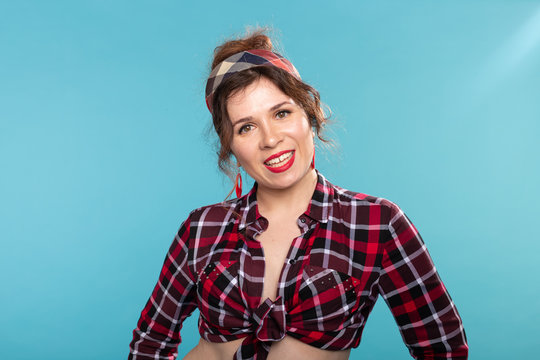 Positive beautiful young woman in a plaid vintage shirt looking at the camera and smiling posing on a blue background.