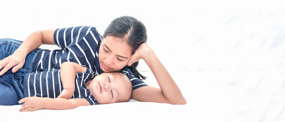 Young Asian women laying down by her baby side while sleeping. Mother takes care of little baby boy in bedroom.