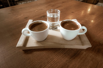 two cups of coffee a water glass on the table