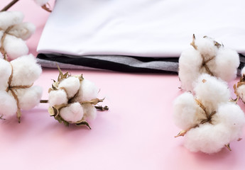 Obraz na płótnie Canvas Delicate white cotton flowers textile clothes on a pink background. Organic cotton clothing idea