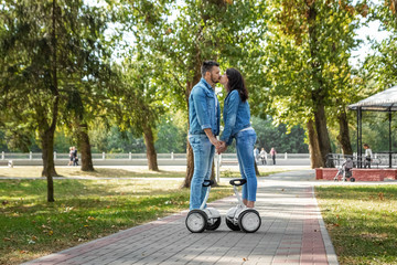 A young couple riding a hoverboard in a park, self-balancing scooter. Active lifestyle technology future