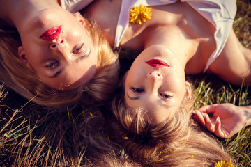 two girls sisters lie on the grass with flowers