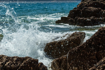 Seascape: stones, sea wave, frozen drops of water, turquoise sea, blue sky. Krk, island of Krk, Croatia.