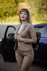 portrait of a young woman in a suit next to a car