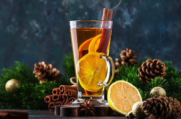 Christmas or New Year hot winter drink, spicy grog cocktail, sangria or mulled wine with tea, lemon, rum, cinnamon, anise. Rustic style, copy space - obrazy, fototapety, plakaty