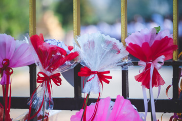The bouquets of flowers wrapped in white, pink and red paper tied with a beautiful red ribbon. Which the trader put on the fence of the educational institution, allow people to buy for congratulation. - Powered by Adobe