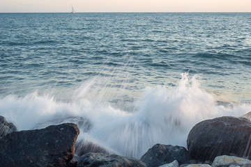 Splash of sea water and foam on the stone shore