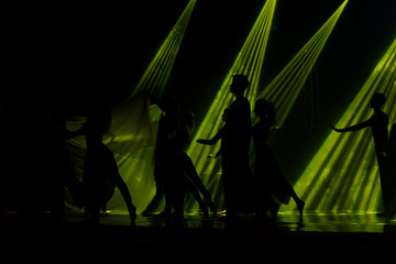 Silhouettes of young people dancing in stage.