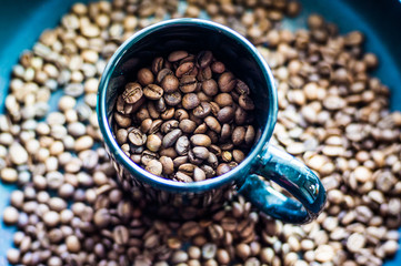 Roasted brown coffee grains in a black cup