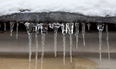 Small icicles spike of ice hanging from the roof element. Subfreezing weather concept