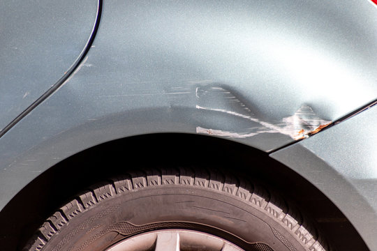 Grauer PKW mit Blechschaden am hinteren Kotflügel zeigt Beschädigung durch einen Auffahrunfall mit Fahrerflucht als Fall für die Unfallversicherung zur Schadensregulierung per Vollkasko oder Gericht