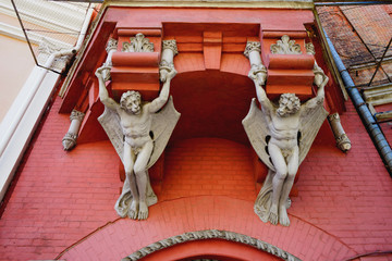 Architectural sculptures two gargoyles under the balcony, view from below.  