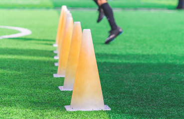 Children feet with soccer boots training on training cone on soccer ground