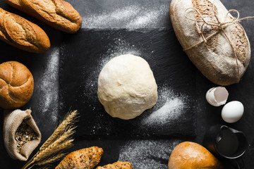 Flat lay of dough and bread on black background