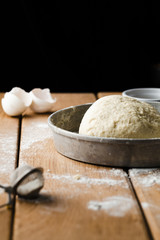Front view of a dough in a tray on wooden table