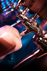 Bartender pouring a large lager beer in tap. Bright and modern neon light, males hands. Pouring beer for client. Side view of young bartender pouring beer while standing at the bar counter.