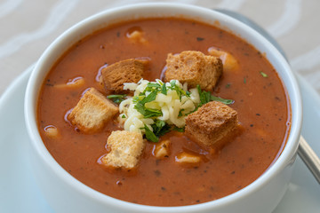 Tomato soup with croutons, cheese and fresh parsley, closeup