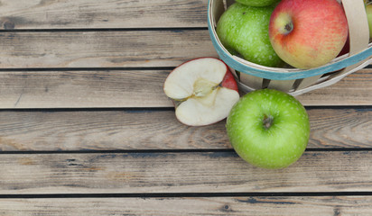 top view on green and red apples on a little basket  on wooden table