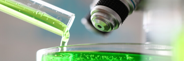 Microscope with green substance pouring out from test tube