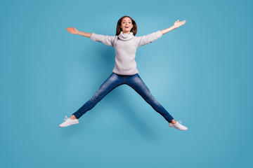 Full size photo of cute candid girl jump like a star feel content wear white sweater pullover denim jeans sneakers isolated over blue color background