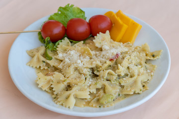 Pasta farfalle with cherry tomato and cheese in white plate, closeup