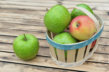 top view on green and red apples on a little basket  on wooden table