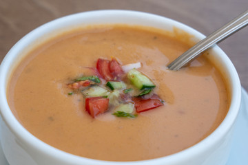 Vegetable cream soup with tomato, potato, squash in a white bowl, closeup