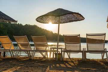 Empty sunbeds and parasols on morning, by the sea. Sand beach in luxury hotel resort near sea. Beautiful morning seascape. Turkey