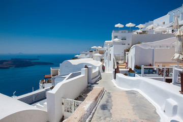 Tourists walking around the beautiful alleys of Fira City at the Santorini Island in a beautiful early spring day - obrazy, fototapety, plakaty