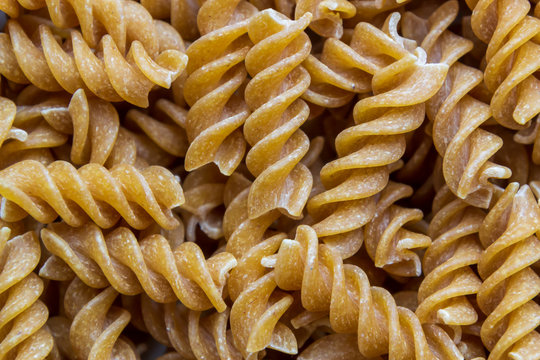 Top view of spiralli whole grain pasta pattern. Flat lay raw spilled Italian pasta view from above
