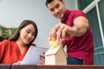 Selective focus of golden coin. Happy Asian couples smiling Because it is profitable from investment And have savings for buying a home and accommodation. Investment concepts and financial planning