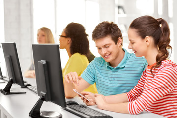 education, technology and learning concept - high school students or classmates with smartphone in computer class