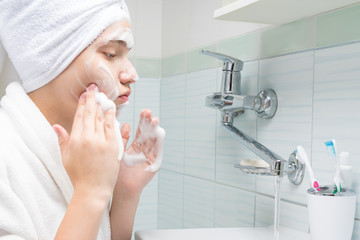 girl washing her face while standing in front of the sink in the bathroom