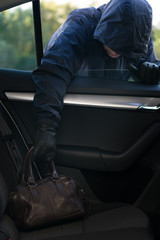 thief steals a brown leather bag from the back of a car through an open window