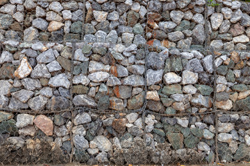 Stone walls for blocking the collapsing stone. Stone background. Stone wall covered with a net. stone gabion wall.