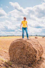 Naklejka na ściany i meble 11 years old caucasian boy in the countryside helps a farmer with grain harvesting