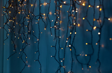 holiday, illumination and decoration concept - bokeh of christmas garland lights over dark blue...