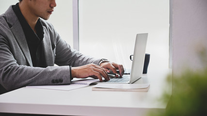 Close-up businessman using laptop computer on table.