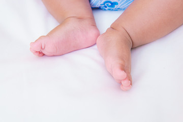 asian baby's feet are sleeping on a white bed sheet with copy space