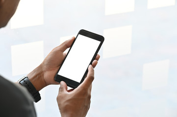 Closeup man hands holding smart phone with blank copy space screen for your text message or information content, male reading text message on cell telephone during in urban setting.