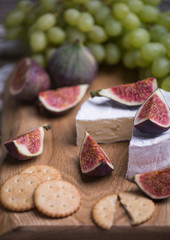 Fresh natural grape, figs and cheese on a wooden board.