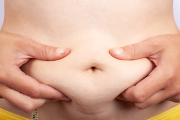 concept: overweight diet.girl with mild obesity hold to her stomach.excess weight after childbirth