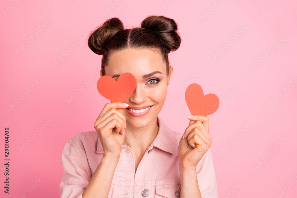 Sticker Portrait of lovely youth holding papercard heart looking with toothy smile wearing jacket isolated over pink background