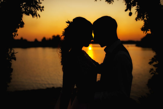 sunset photo of a couple on the background of a wedding arch