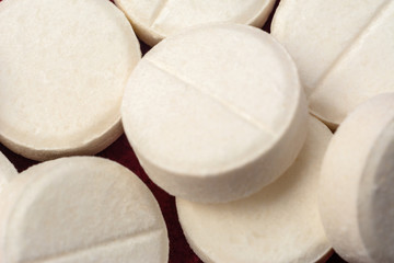Fototapeta na wymiar White round pills on red background, texture of pills.