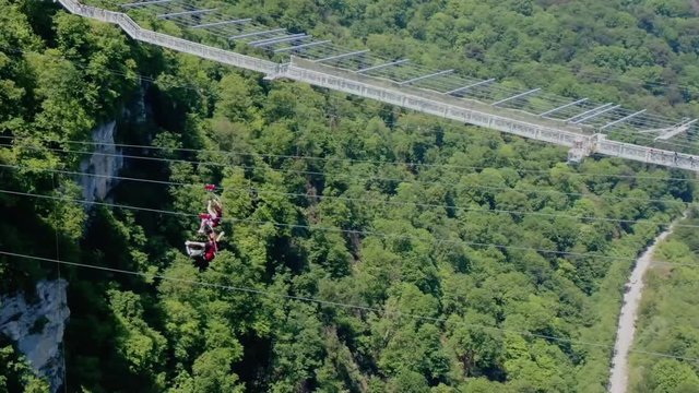 Sochi, Russia - may 2019. Aerial view cheerful people riding on zipline in Sochi Skypark AJ Hackett, Zoom in shot