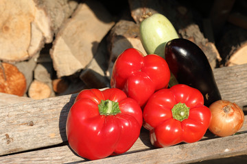 Ripe sweet peppers, zucchini and onions from the infield. Lying on wooden boards, bathed in sunlight.